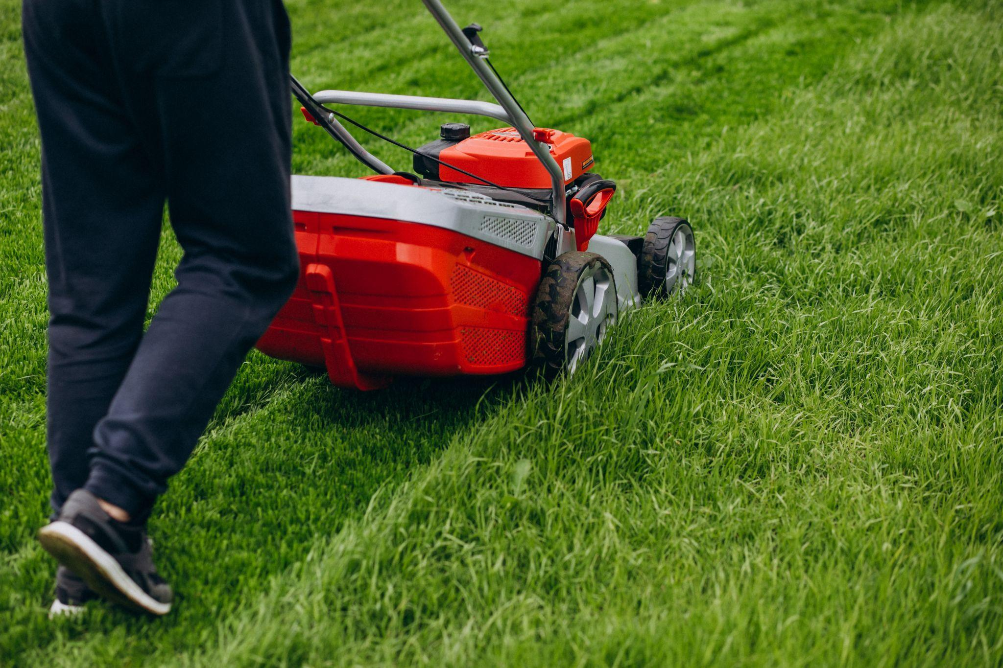 A person mowing the lawn with a red lawnmower