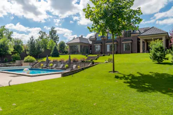 An image of a backyard with a pool and green grass