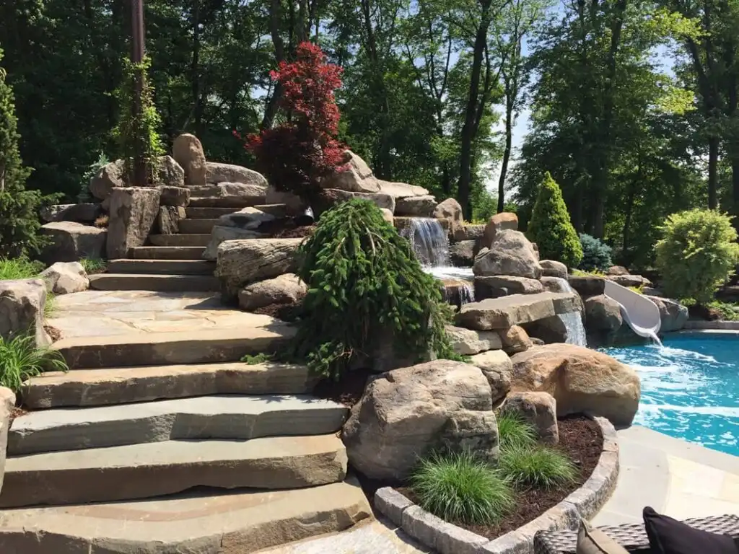 An image of a fountain and a slide leading to a pool with stone staris next to it