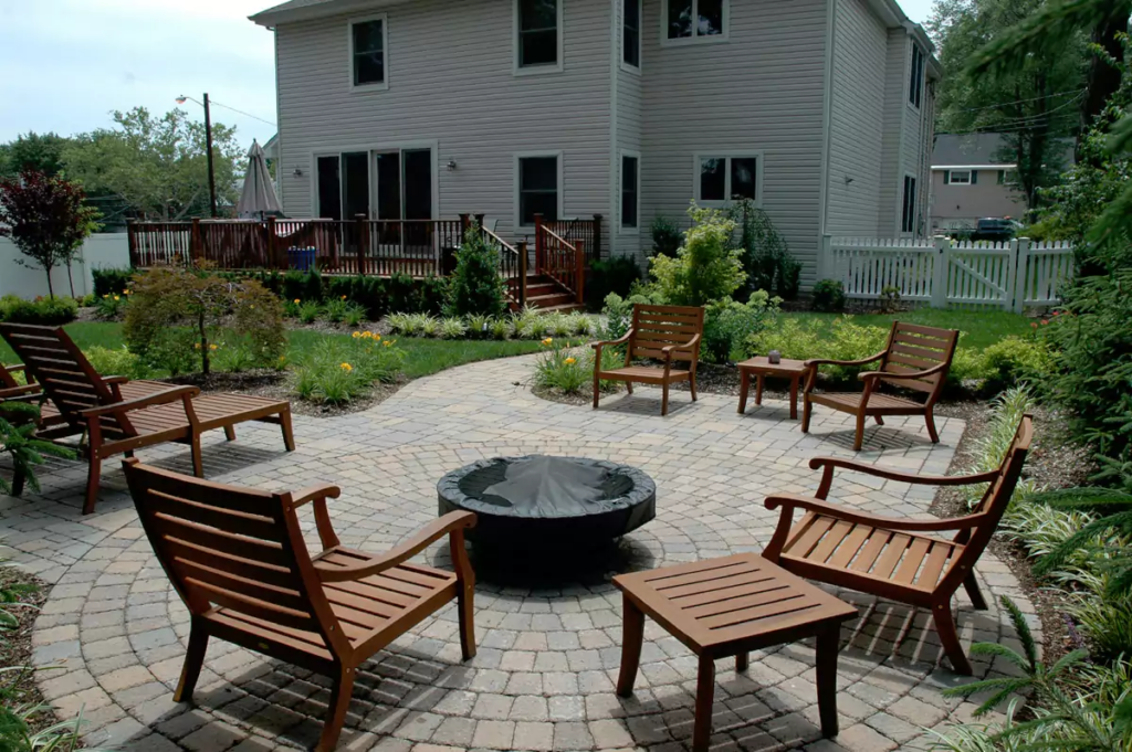 Outdoor seating area with fire pit and grill features in a landscaped backyard